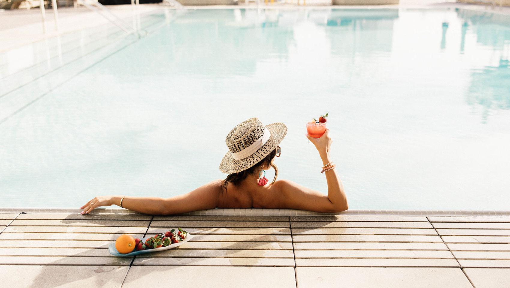 woman in pool with cocktail